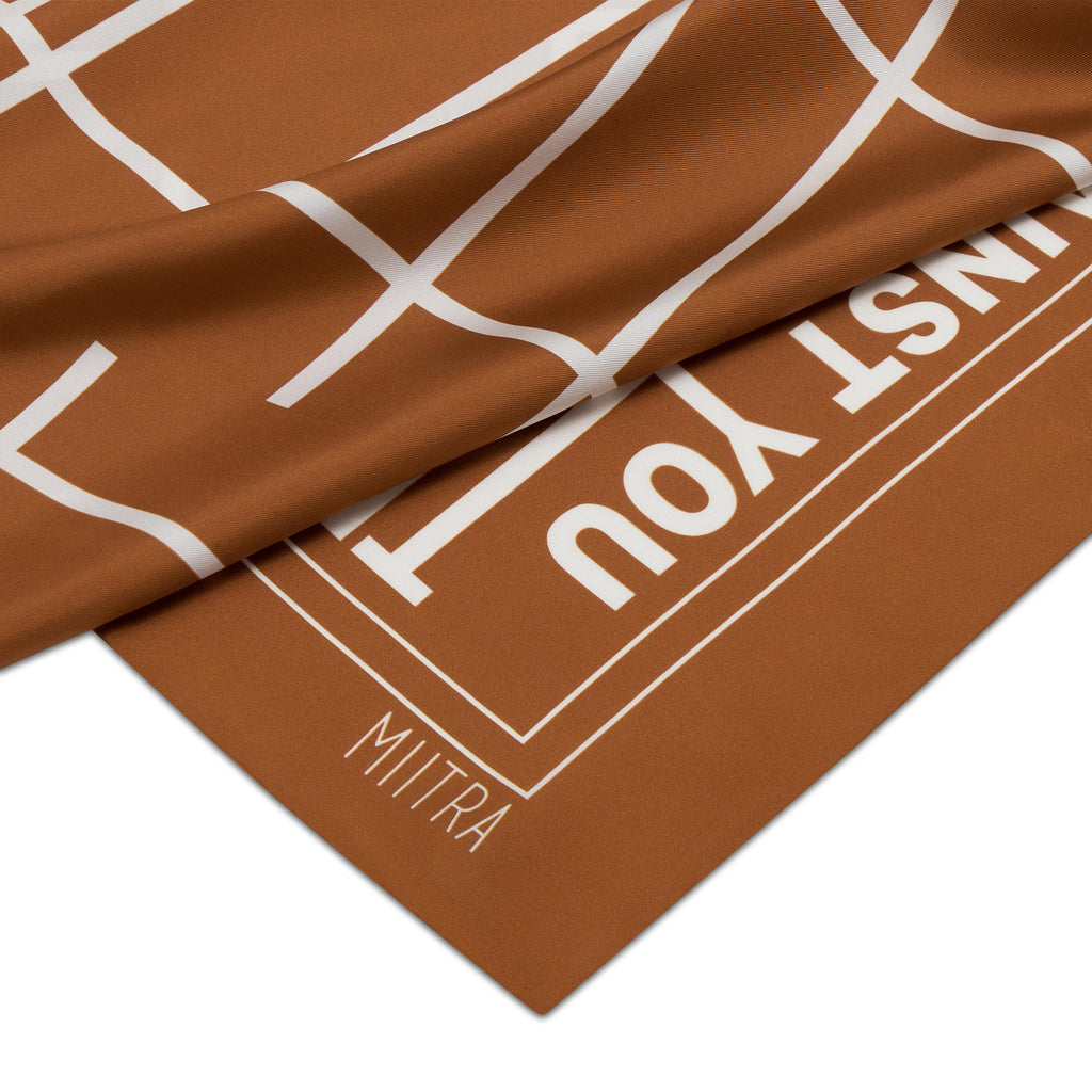 Close up view of the MIITRA logo on a brown silk scarf
