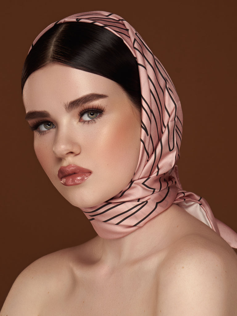 Woman wearing a light pink silk scarf as a headwrap.