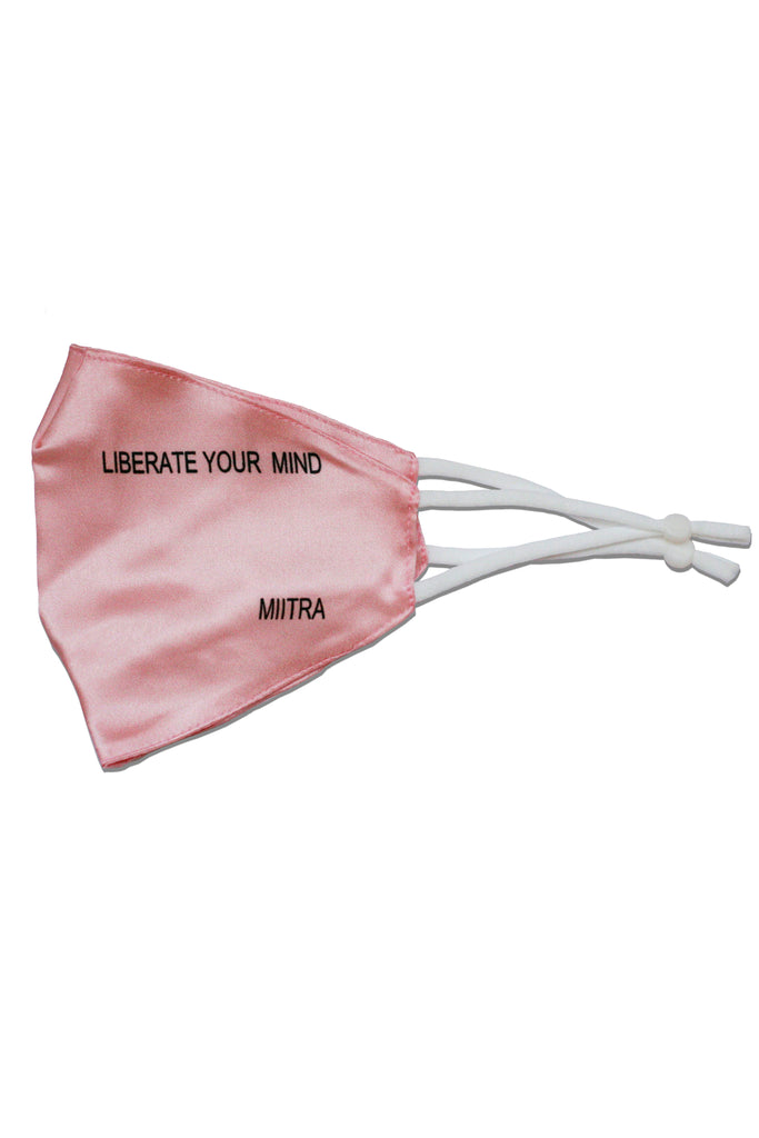 Pink silk face mask that has liberate your mind printed on it. MIITRA logo is also printed on the mask.