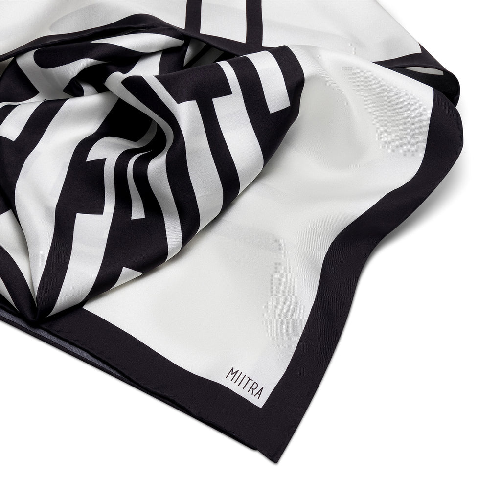 Liberation Silk Scarf - detail shot of ivory and black silk scarf with close up of branding