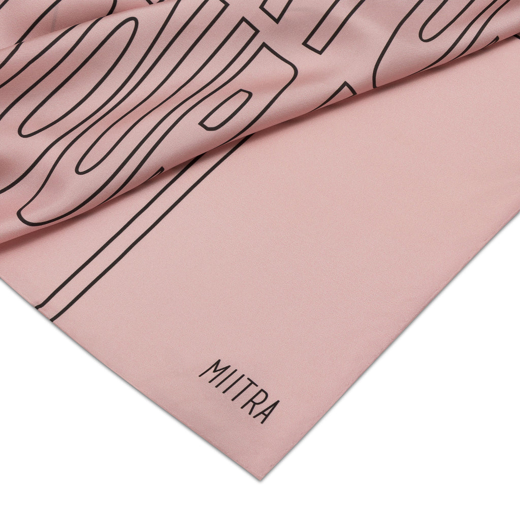 A close up view of the MIITRA logo on a pink silk scarf