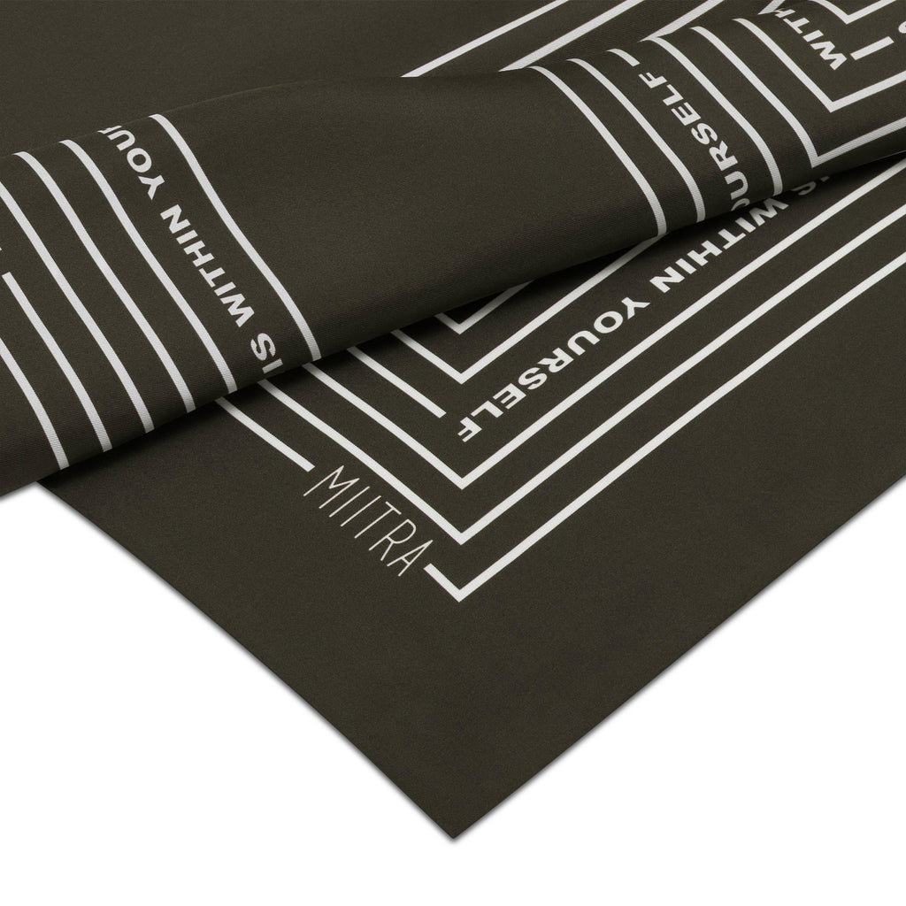 Close up view of the MIITRA logo on an olive brown silk scarf