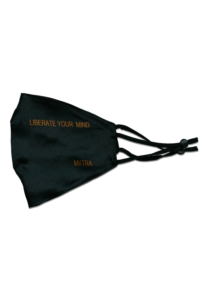 Black silk face mask that has liberate your mind printed on it. MIITRA logo is also printed on the mask.