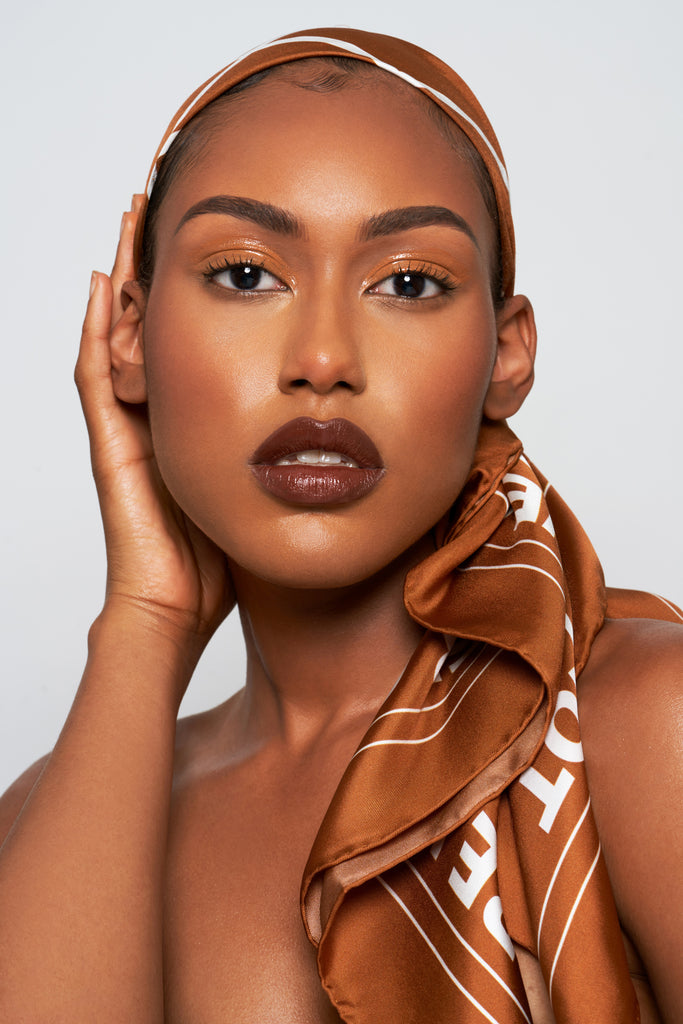 Black woman wearing a brown silk scarf as a headscarf.